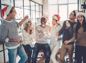 Feiernde MitarbeiterInnen mit Weihnachtsmützen