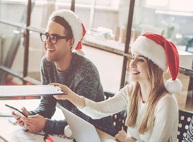 Mitarbeiterin mit Weihnachtsmütze reicht ihrem Gegenüber Dokumente