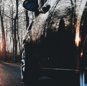 Schwarzes Auto fährt bei Sonnenuntergang in einen Wald