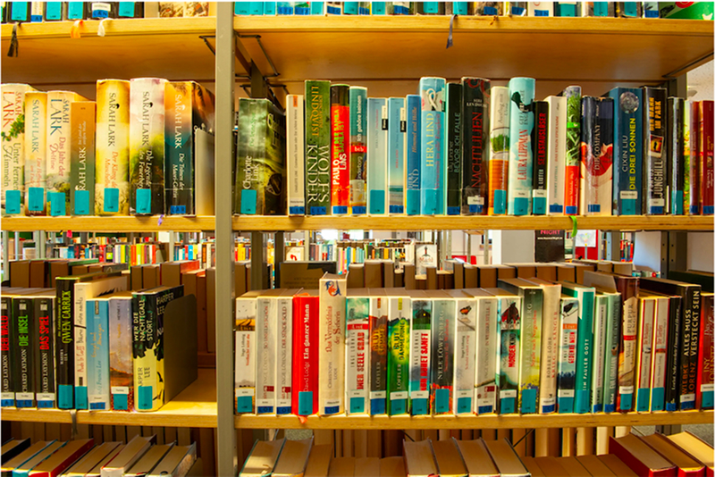 Bücherregal mit zahlreichen bunten Büchern in einer Bibliothek.