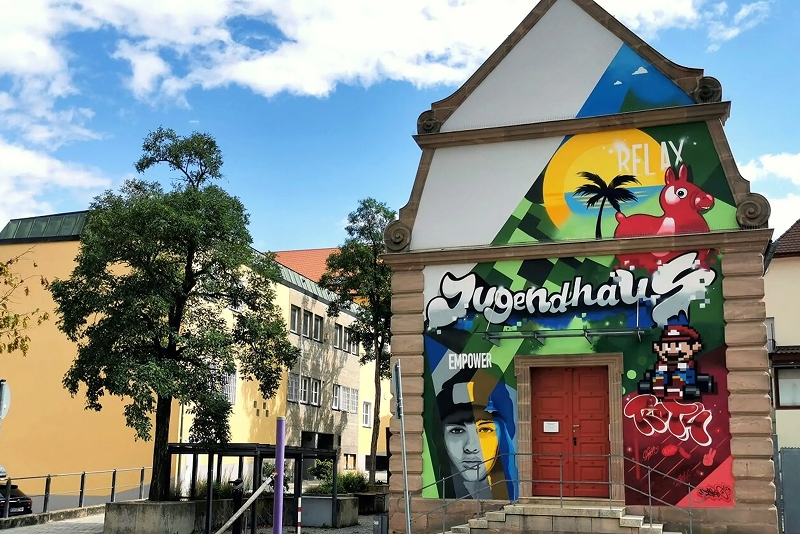 Gebäude mit bunter Graffiti-Fassade und kreativem Eingangsbereich.