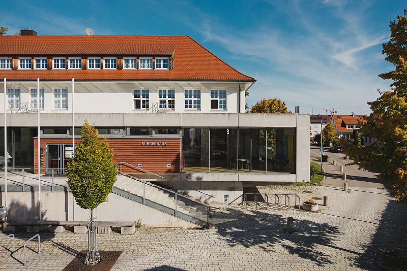 Bürgerhaus mit modernem Anbau und Vorplatz.