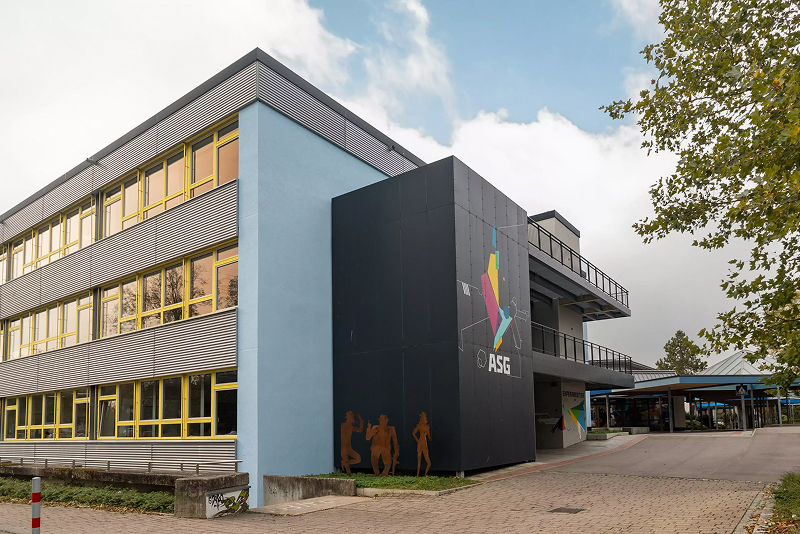Modernes Schulgebäude mit großen Fenstern und farbigen Akzenten an der Fassade.