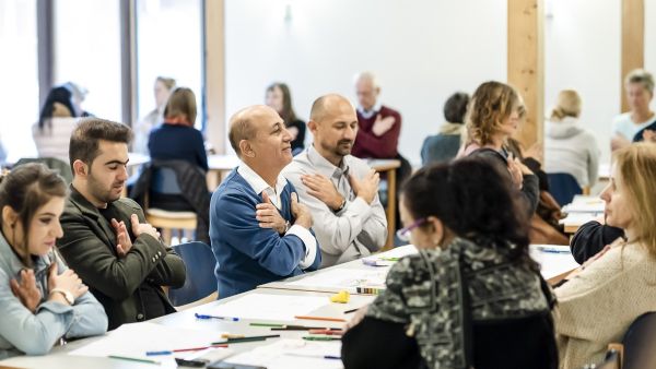 Seminarteilnehmende üben die Butterfly-Übung, Arme überkreuzt vor der Brust, konzentriert.