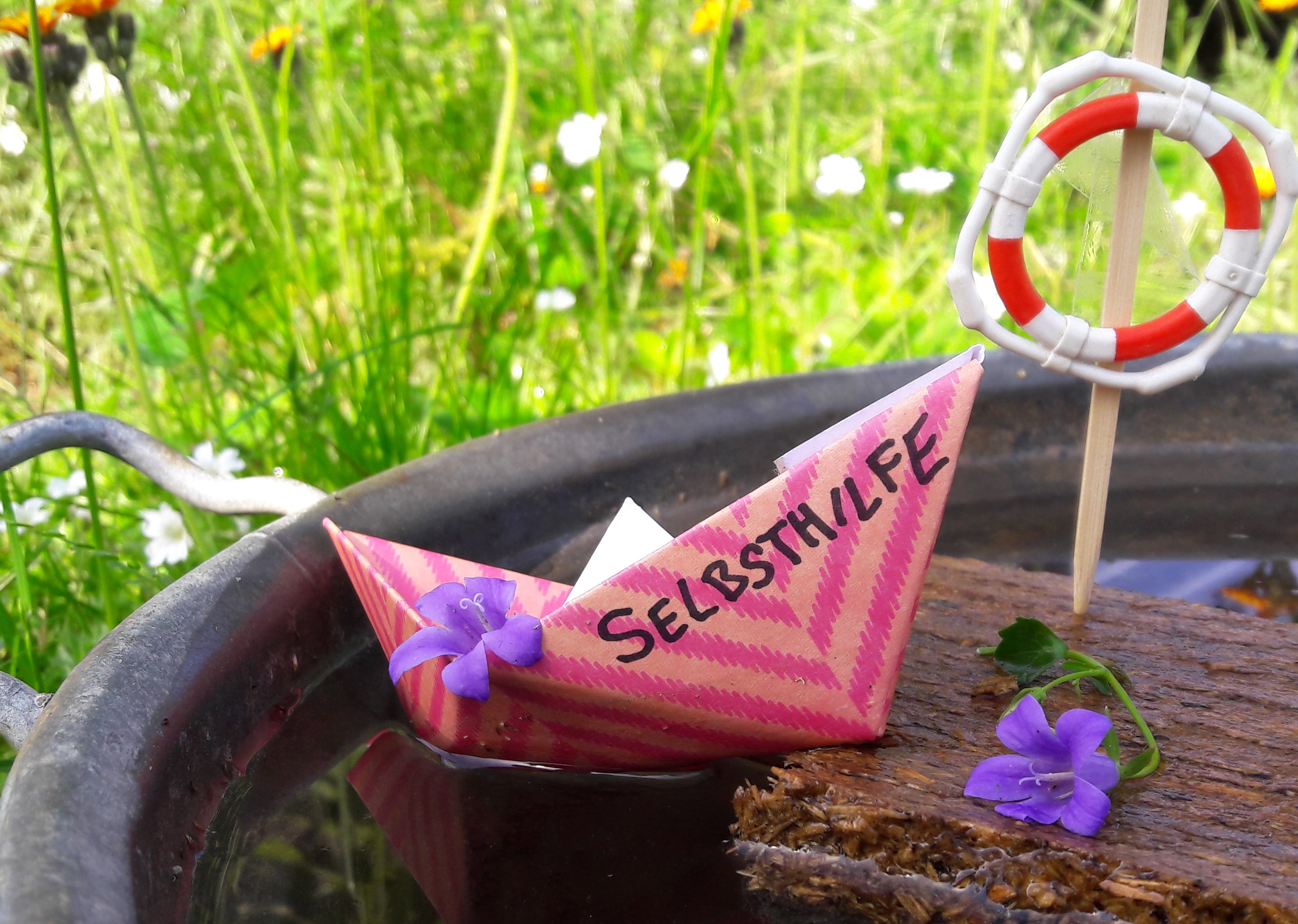 Ein Papierschiff mit der Aufschrift "Selbsthilfe"