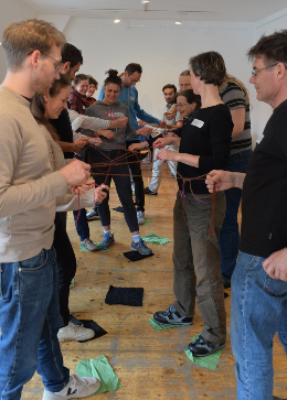 Auf dem Bild sind viele Menschen zu sehen, die gemeinsam eine Schnur halten, die sie miteinander verbindet. 