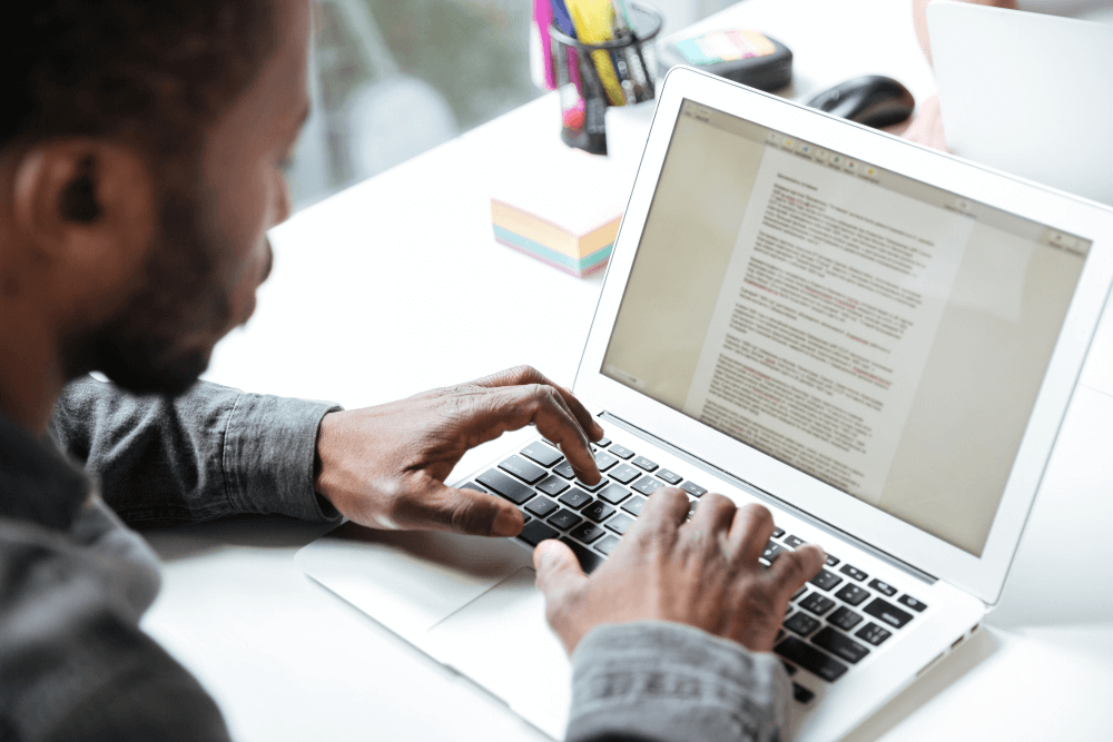 A man types a manuscript on his computer for print on demand