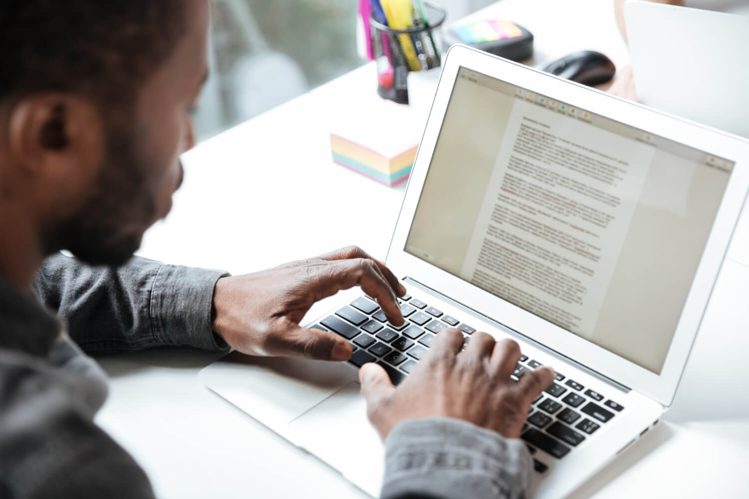 A man sits at a computer typing a manuscript for a book