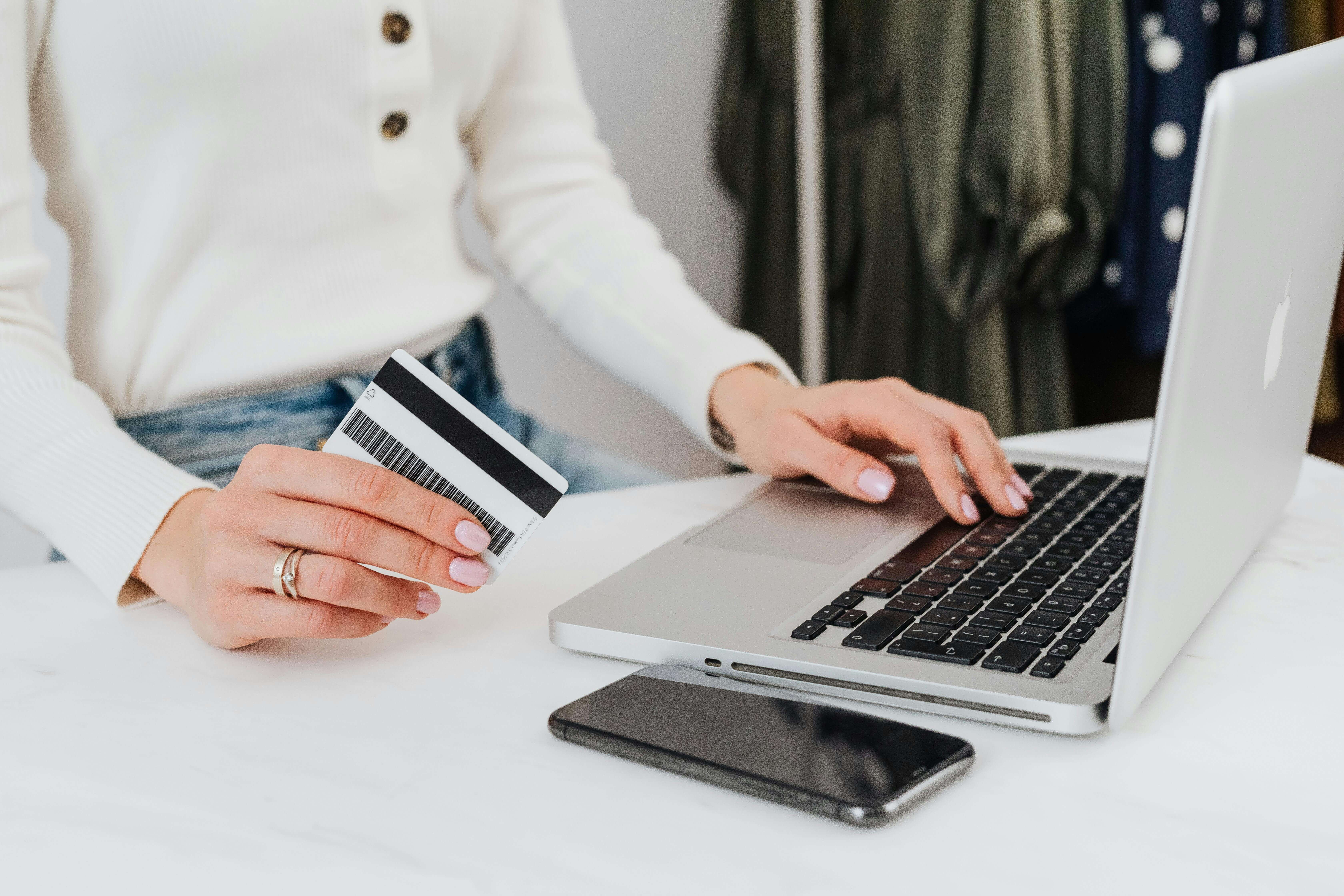 A woman sitting in front of a computer at a desk with a payment card in her hand.