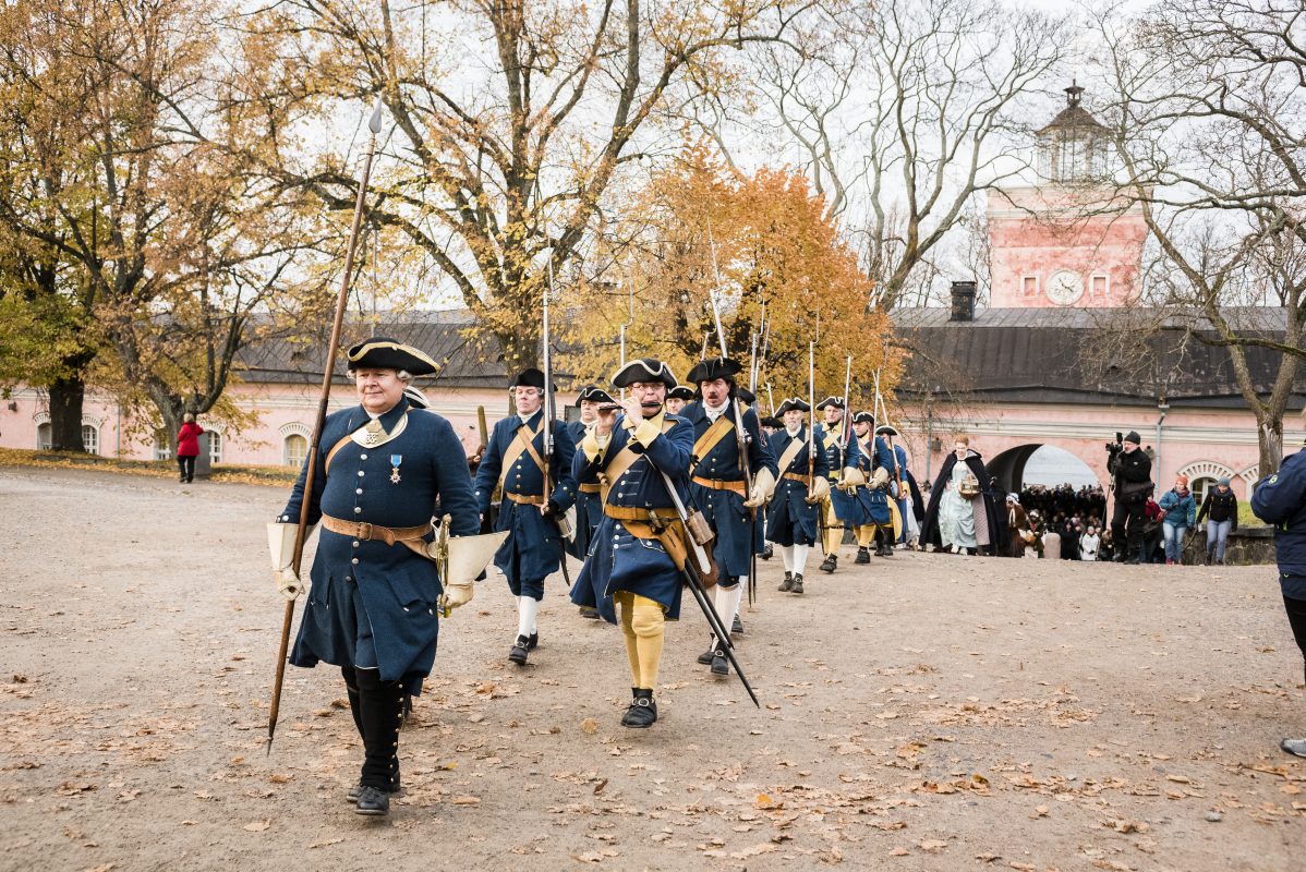 Vanha Warusväki kävelemässä univormuissa läpi Rantakasarmin holvikaaren.