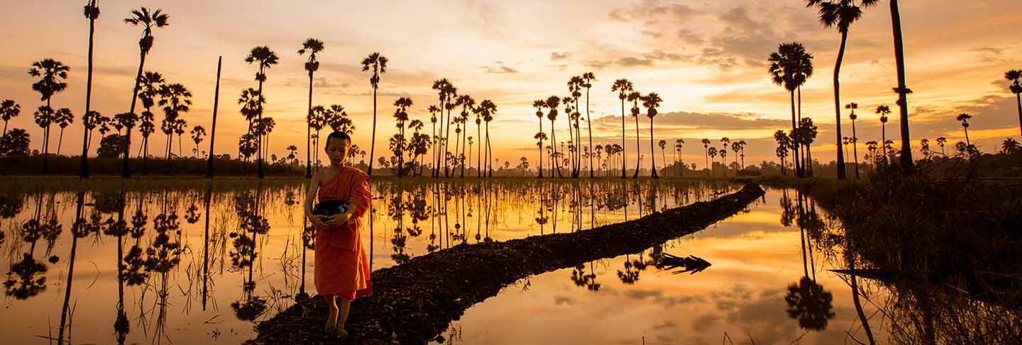 Novice monk were walking through the waterfront of the rice fields in the morning to perform the mission of the monks in the golden light in the morning.