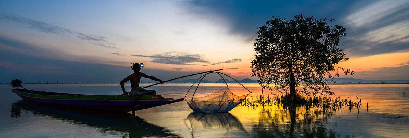 Fisherman on boat catching fish with sunrise