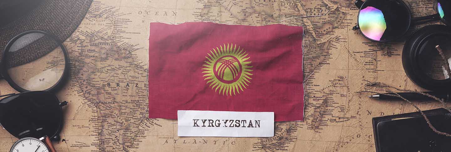 Kyrgyzstan flag between traveler's accessories on old vintage map.