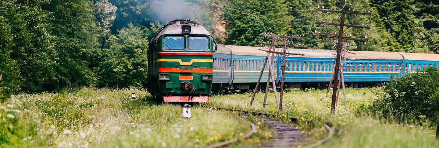 Locomotive with wagons riding railroad in carpathian mountains. train with passengers turning on railway. travel and tourism