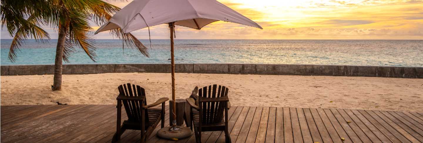 Umbrella and deck chairs on the beautiful tropical beach and sea at sunset time for travel and vacation
