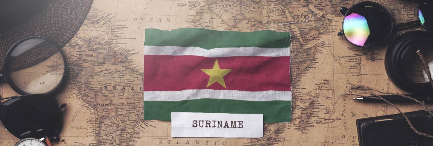 Suriname flag between traveler's accessories on old vintage map