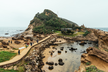 Aerial view diversity of tourists walking in yehliu geopark, a cape on the north coast of taiwan. a landscape of honeycomb and mushroom rocks eroded by the sea.