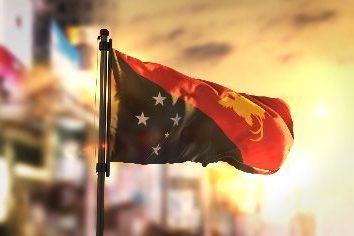 Papua new guinea flag against city blurred background at sunrise backlight