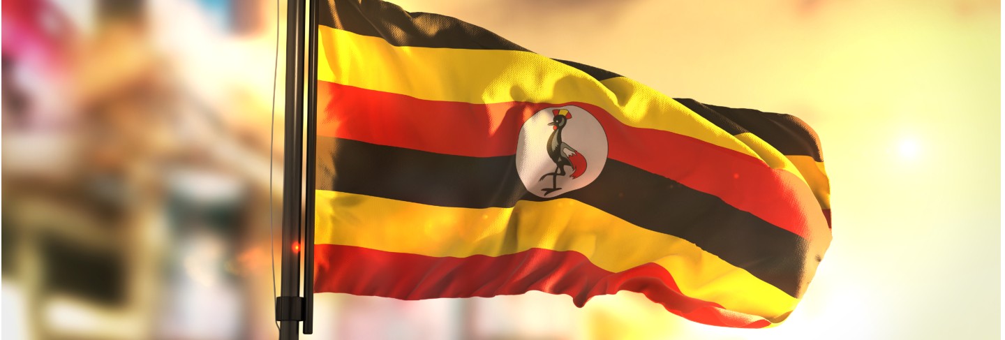 Uganda flag against city blurred background at sunrise backlight