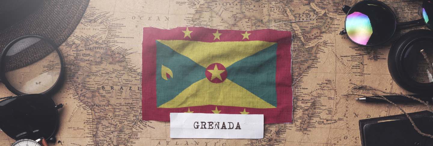 Grenada flag between traveler's accessories on old vintage map. overhead shot