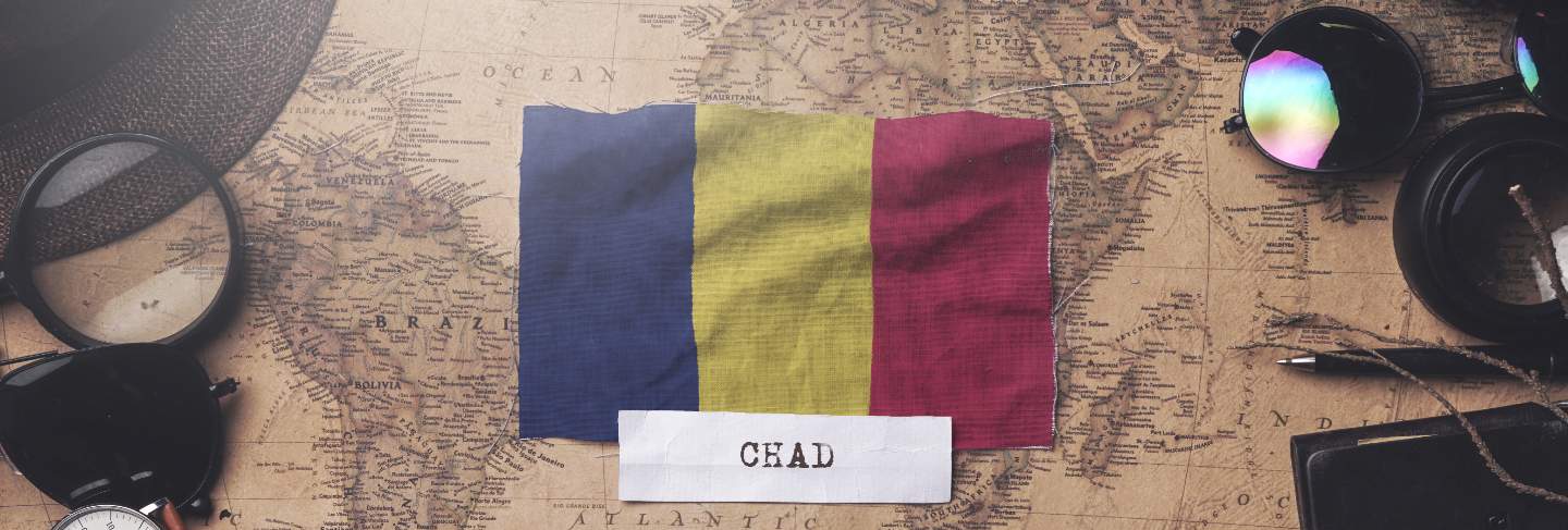 Chad flag between traveler's accessories on old vintage map. overhead shot