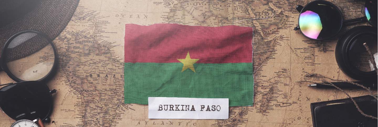 Burkina faso flag between traveler's accessories on old vintage map. overhead shot