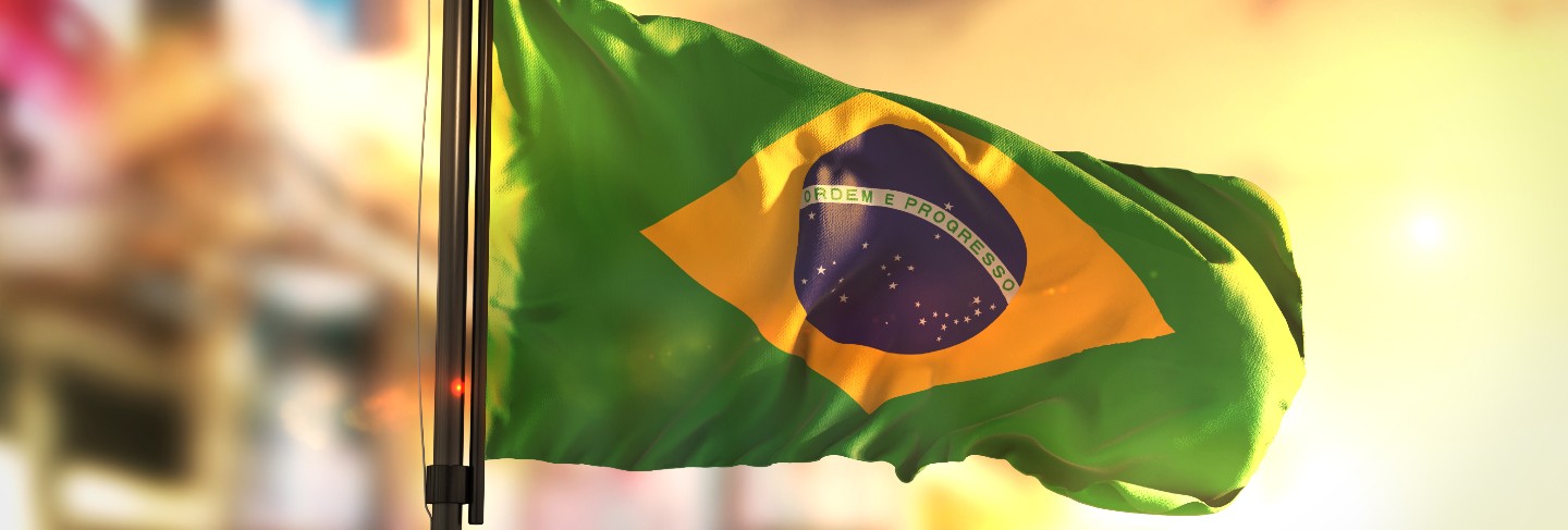 Brazil flag against city blurred background at sunrise backlight