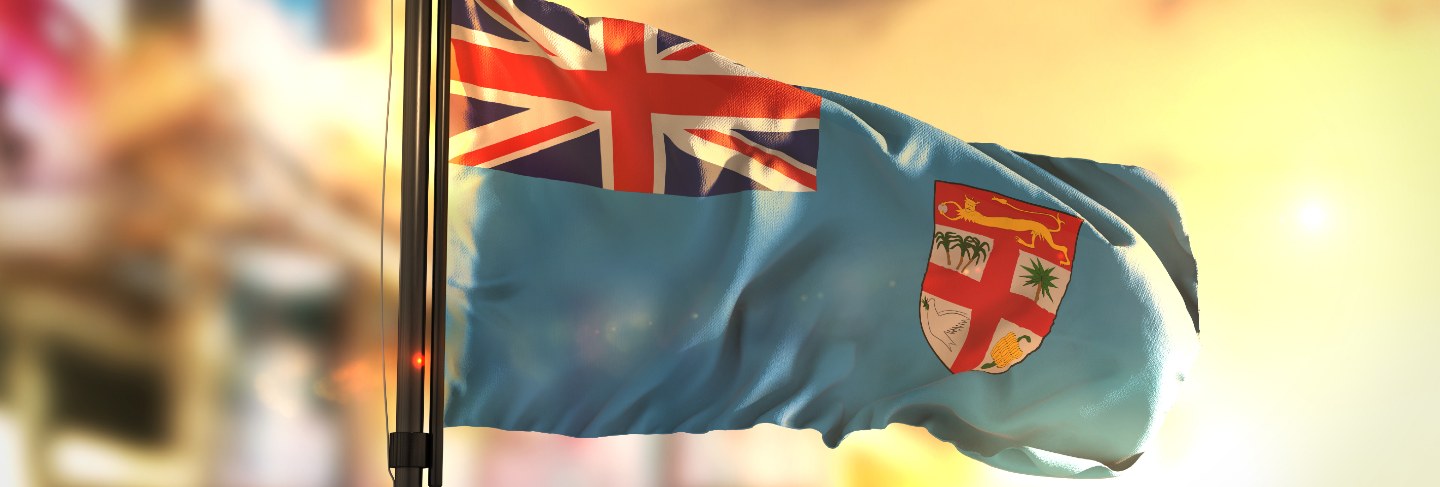Fiji flag against city blurred background at sunrise backlight