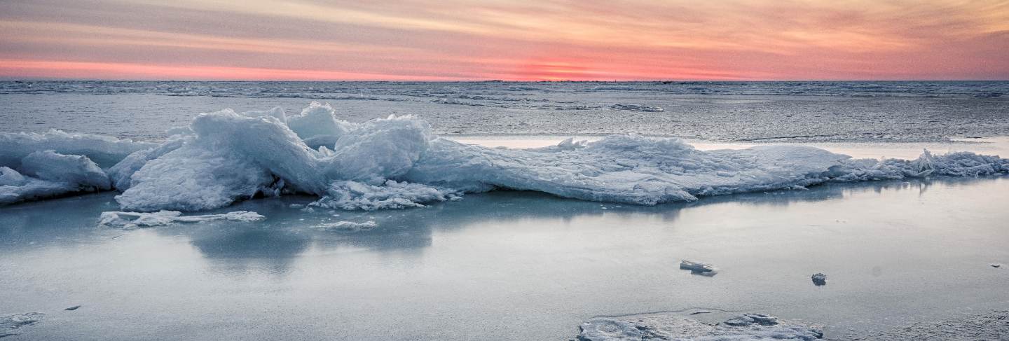 Abstract frozen winter sunrise seascape with ice and colored the sky