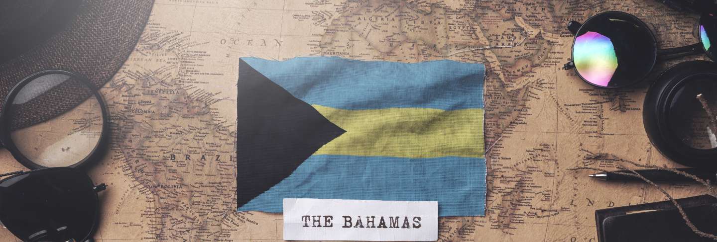 The bahamas flag between traveler's accessories on old vintage map. overhead shot