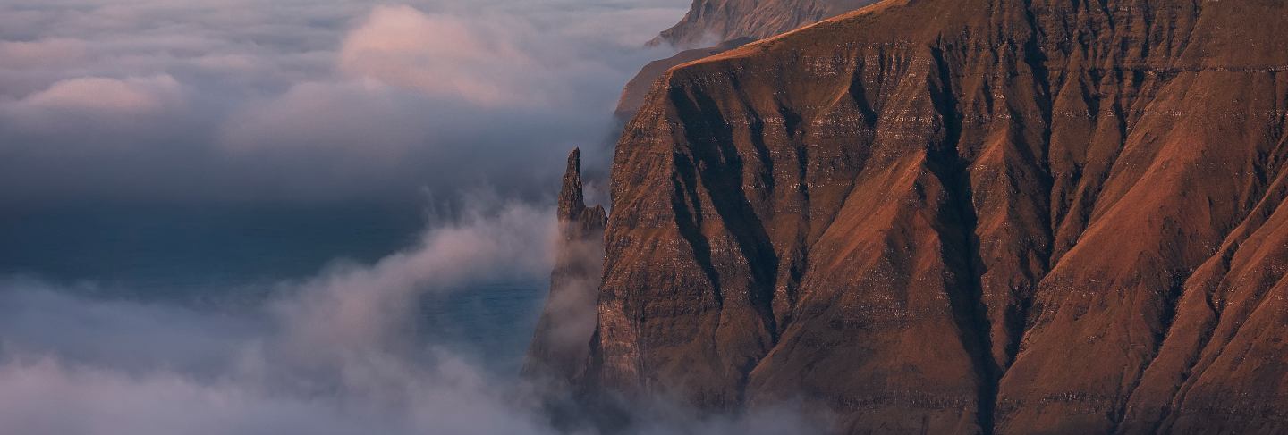 Rock witch's finger at dawn. clouds covered the atlantic ocean. faroe islands, europe.