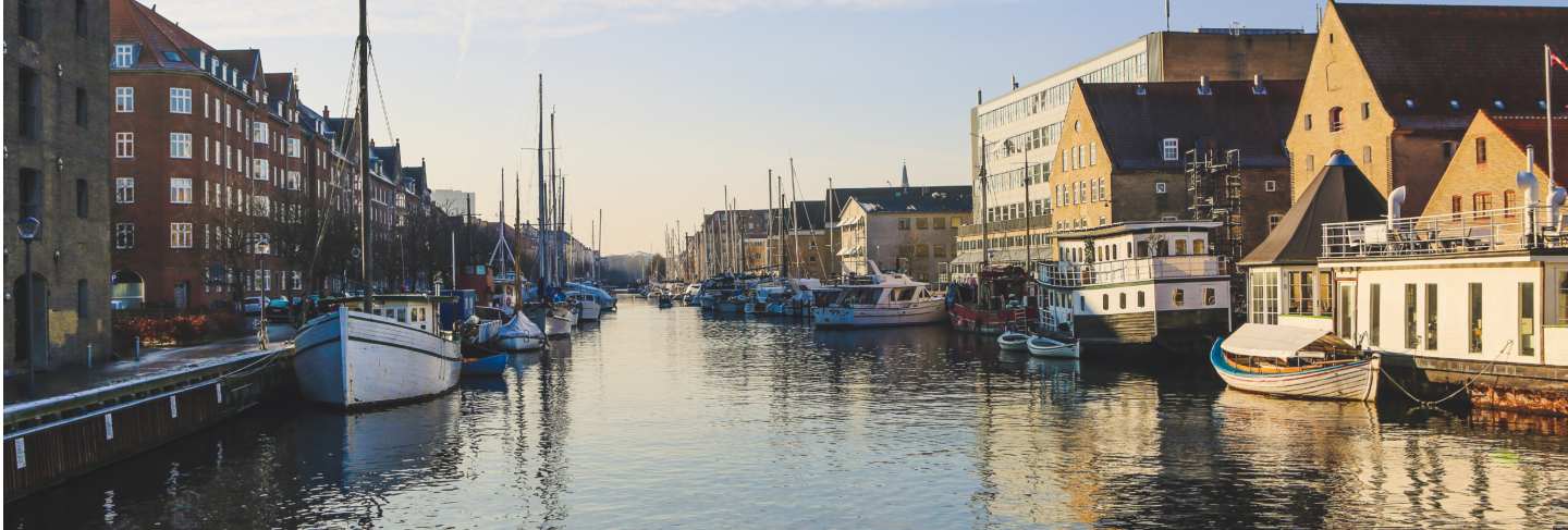 Wide shot of boats on the body of water near buildings in christianshavn, copenhagen,