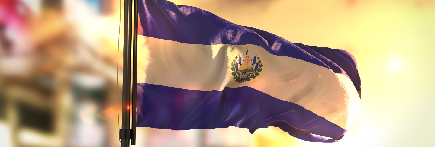 El salvador flag against city blurred background at sunrise backlight