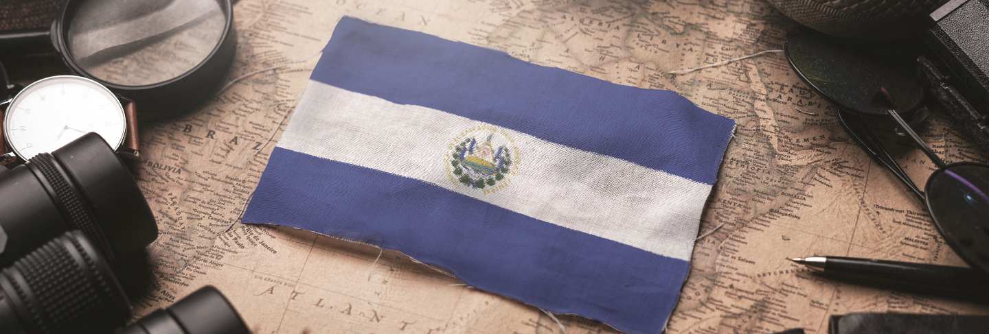 El salvador flag between traveler's accessories on old vintage map