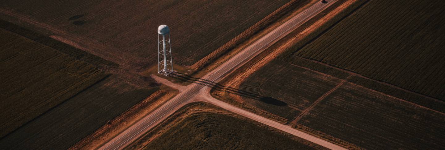 Beautiful aerial shot of narrow roads intersection in the countryside with a white tower
