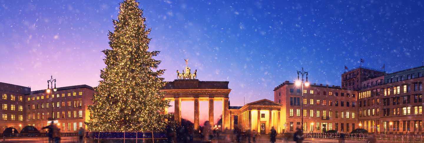 Brandenburg gate in berlin with christmas tree and falling snow in the evening