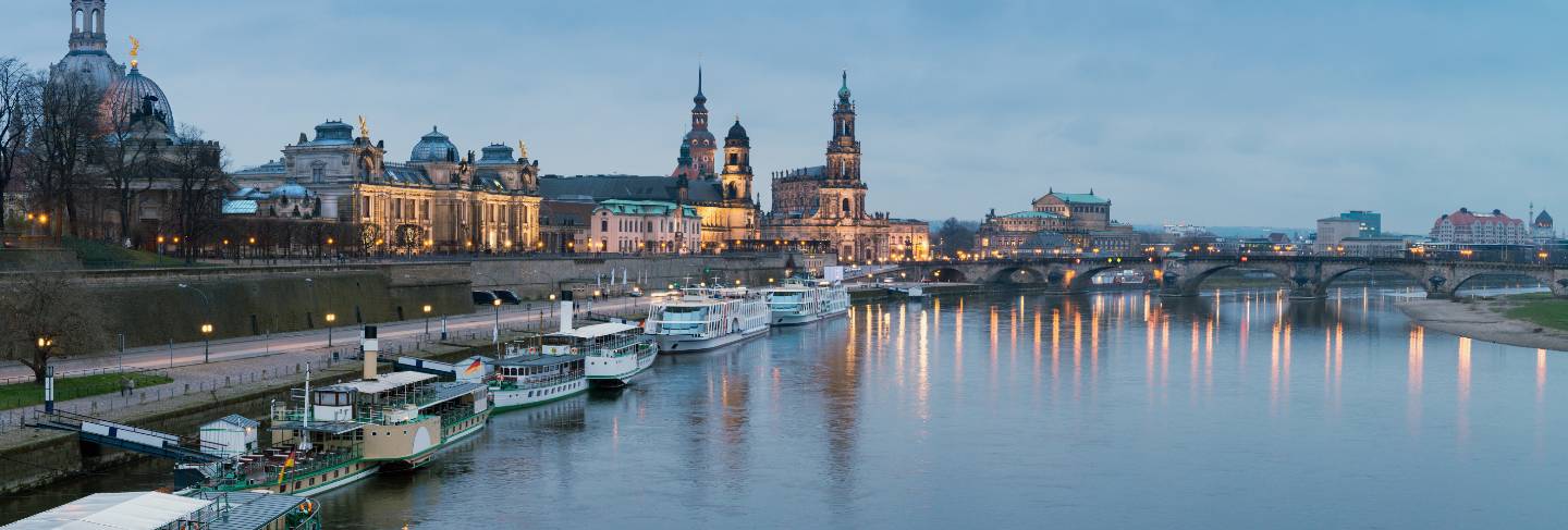 Night panorama of dresden old town with reflections in elbe river and passenger ships