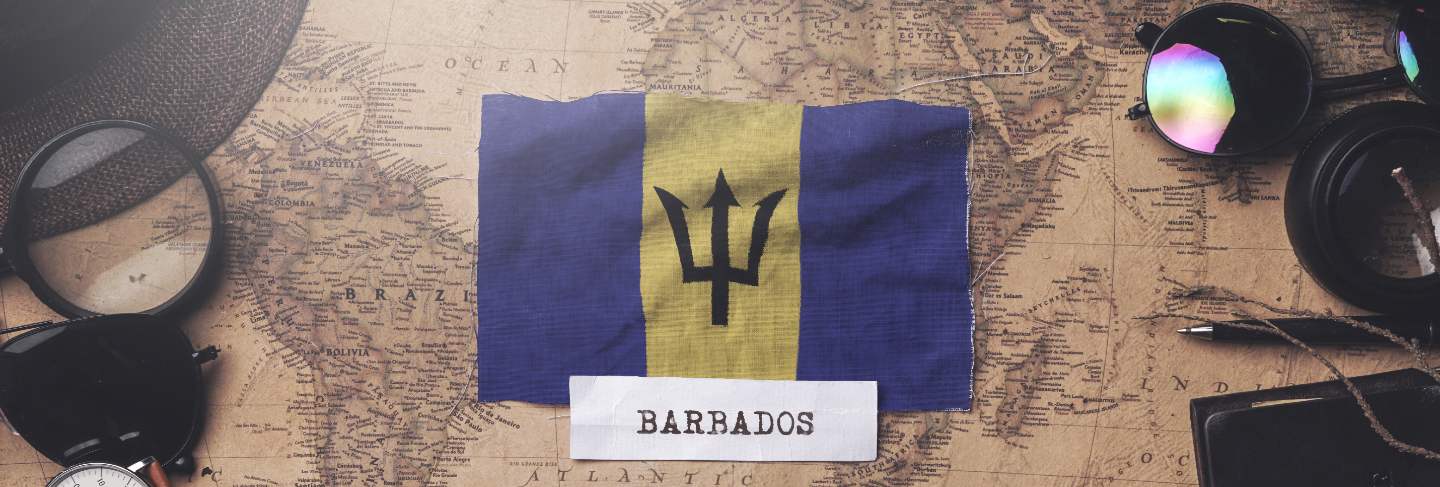 Barbados flag between traveler's accessories on old vintage map.