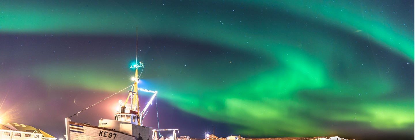 Colourful northern lights with a boat in the foreground in iceland