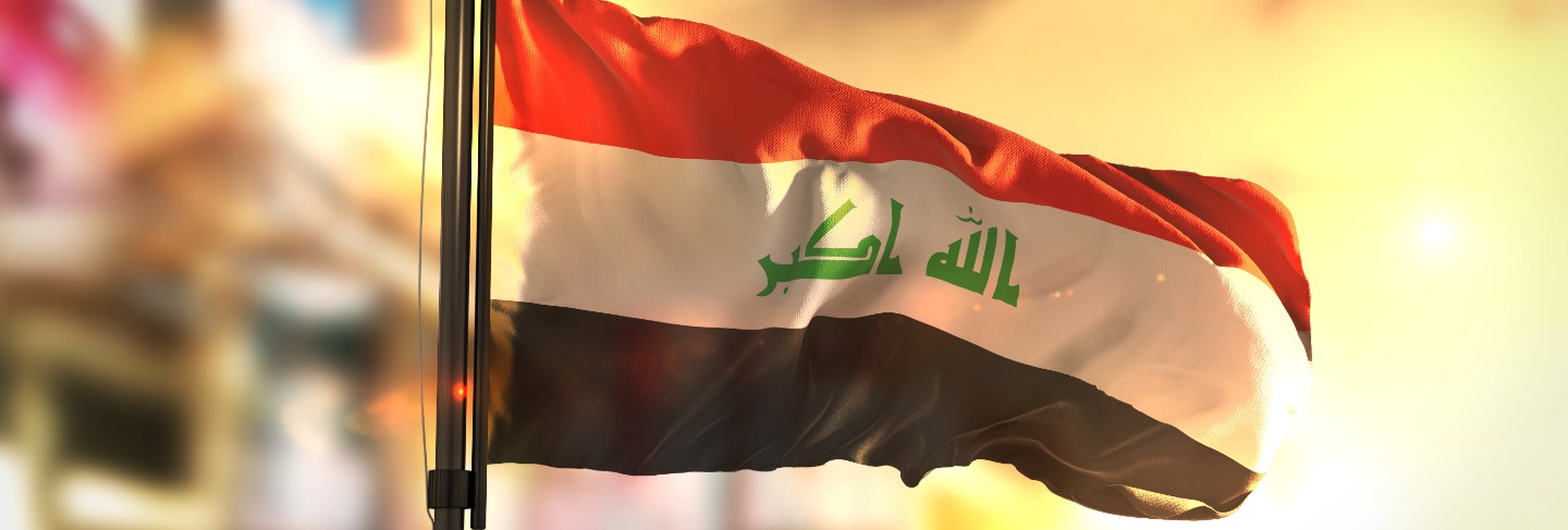 Iraq flag against city blurred background at sunrise backlight