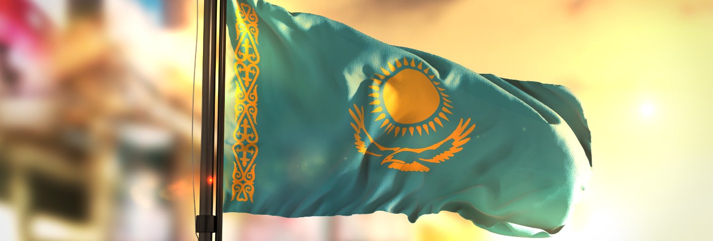 Kazakhstan flag against city blurred background at sunrise backlight