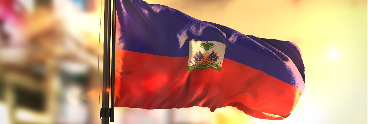 Haiti flag against city blurred background at sunrise backlight