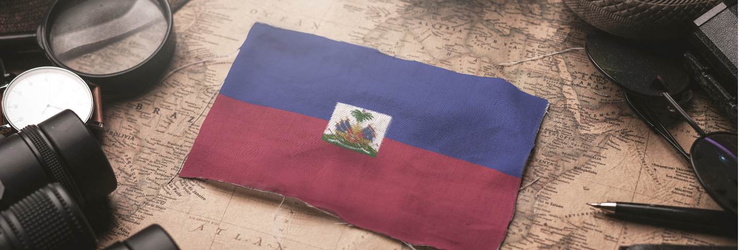 Haiti flag between traveler's accessories on old vintage map. tourist destination concept.