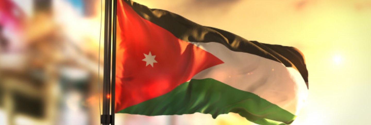 Jordan flag against city blurred background at sunrise backlight