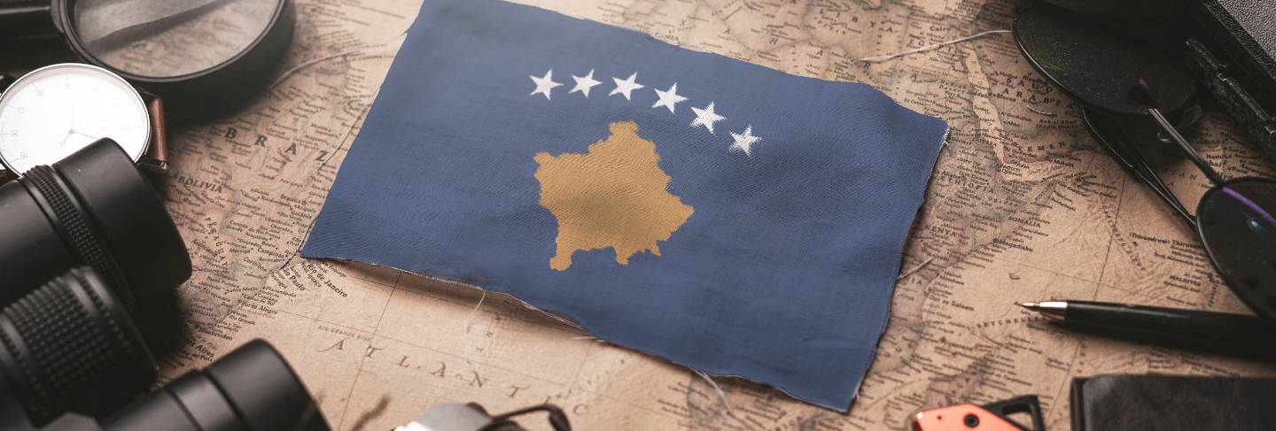 Kosovo flag between traveler's accessories on old vintage map. tourist destination concept.