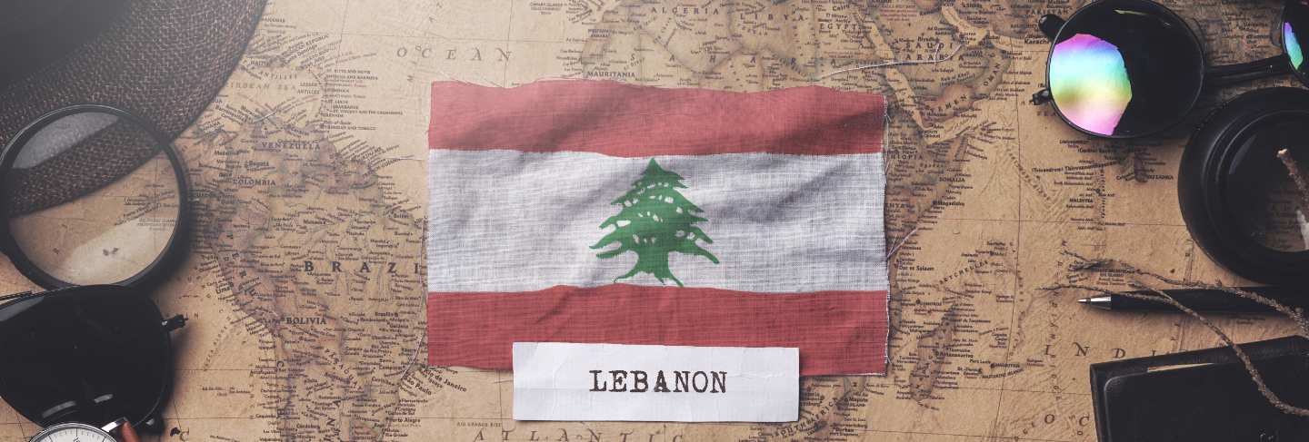 Lebanon flag between traveler's accessories on old vintage map. overhead shot