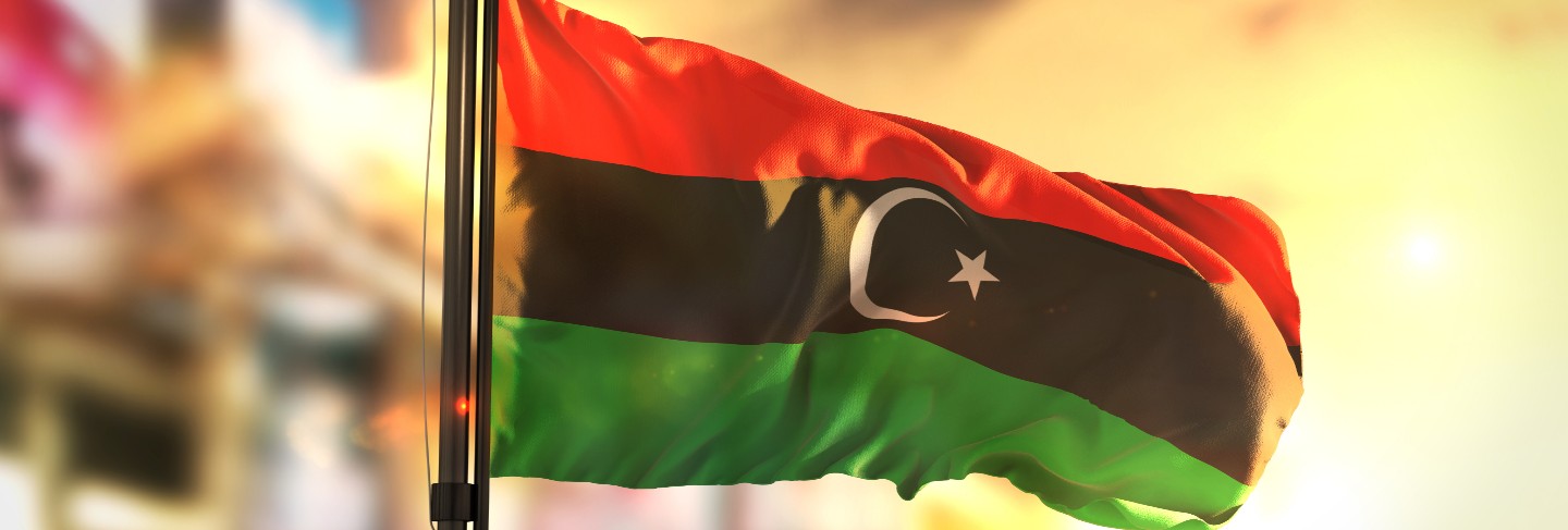 Libya flag against city blurred background at sunrise backlight