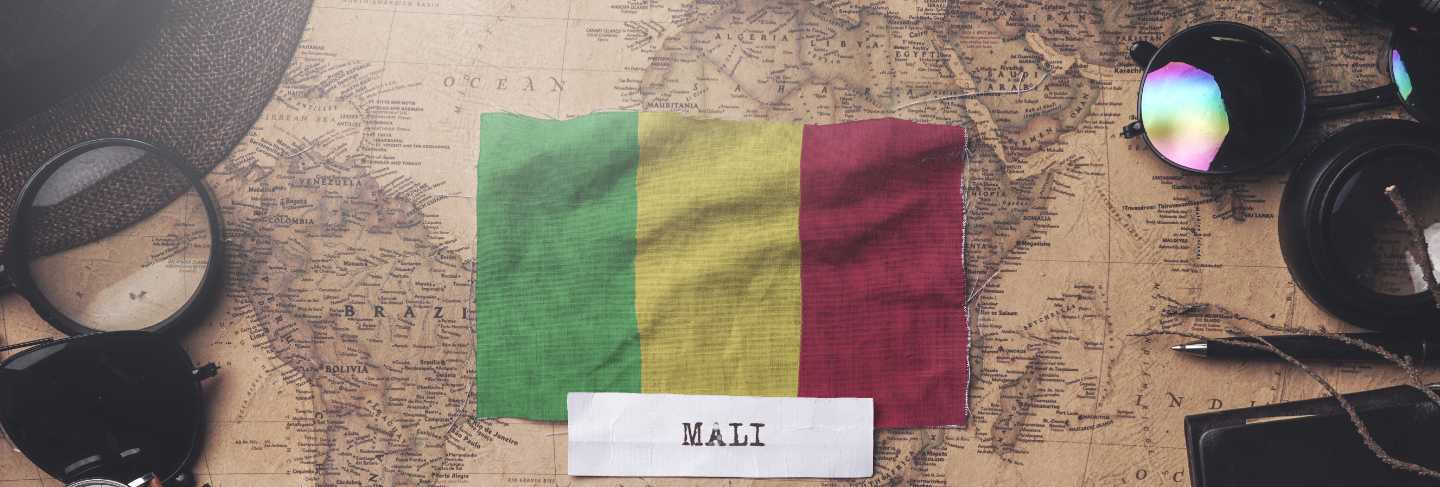 Mali flag between traveler's accessories on old vintage map. overhead shot