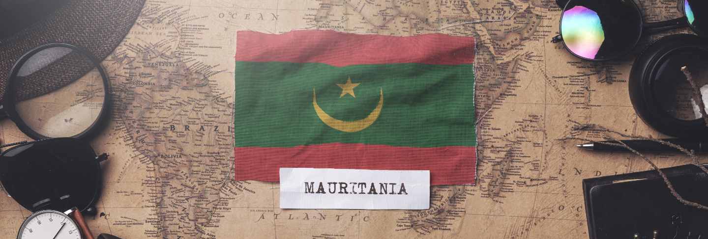 Mauritania flag between traveler's accessories on old vintage map. overhead shot