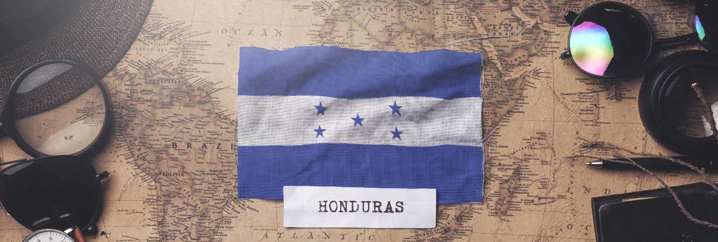 Honduras flag between traveler's accessories on old vintage map. overhead shot